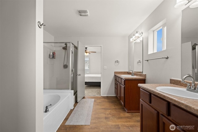 full bathroom featuring a stall shower, wood finished floors, two vanities, and a sink