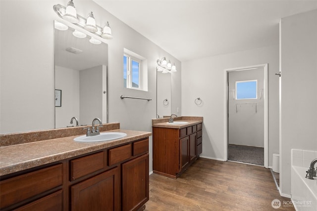 full bath with a sink, two vanities, and a healthy amount of sunlight