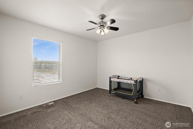 empty room with visible vents, baseboards, ceiling fan, and dark colored carpet