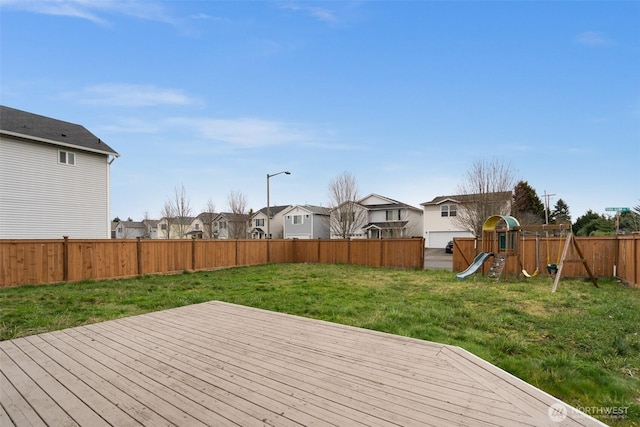 wooden terrace featuring a yard, a residential view, a playground, and a fenced backyard