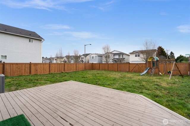 deck with a playground, a yard, a fenced backyard, and a residential view