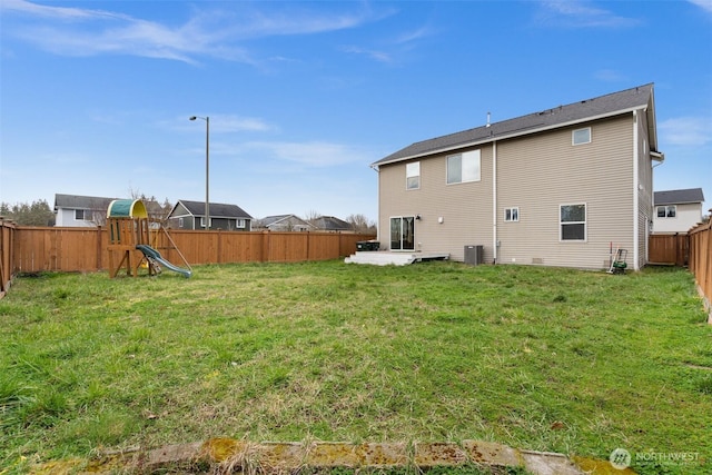 back of property with cooling unit, a fenced backyard, a playground, a patio area, and a lawn