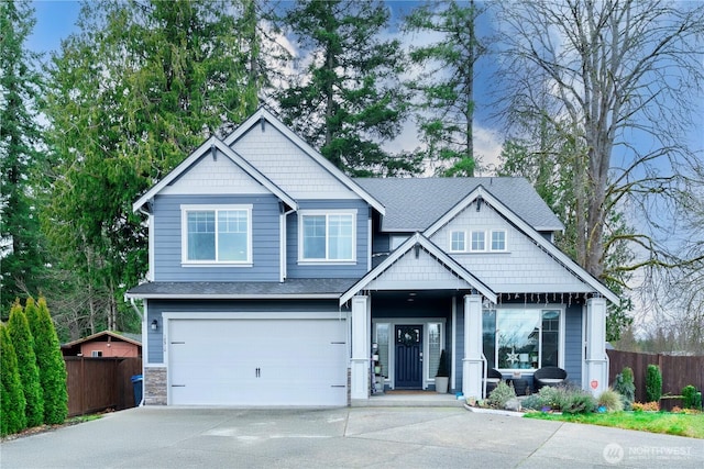 craftsman-style home with an attached garage, stone siding, fence, and concrete driveway