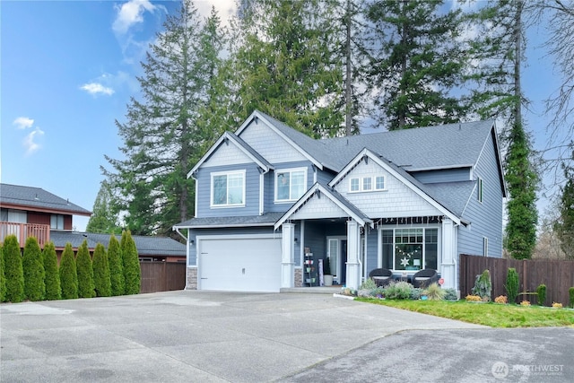 craftsman-style house featuring an attached garage, stone siding, fence, and concrete driveway