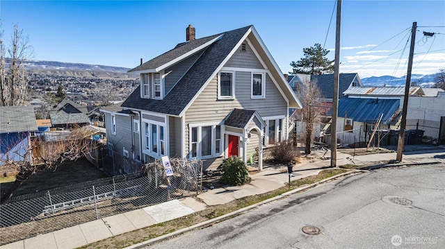 bungalow featuring fence private yard, a shingled roof, and a chimney