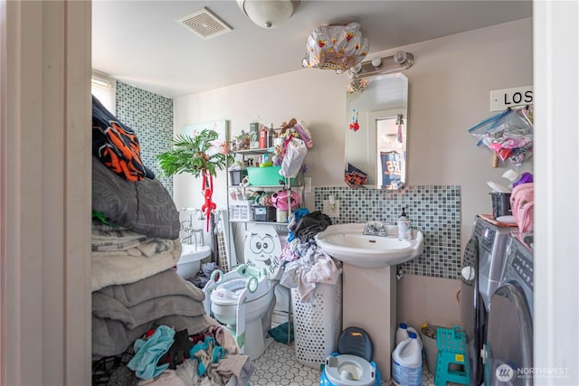 bathroom featuring tile walls, visible vents, washer and clothes dryer, and tile patterned floors