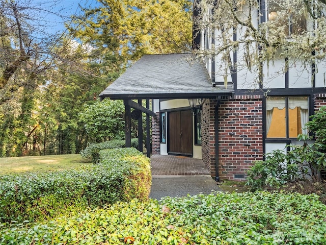 exterior space with roof with shingles and brick siding