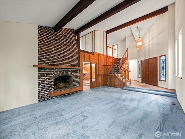 unfurnished living room featuring high vaulted ceiling, carpet floors, stairs, a brick fireplace, and beamed ceiling