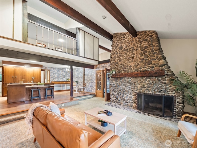 living area with beam ceiling, a stone fireplace, and a towering ceiling