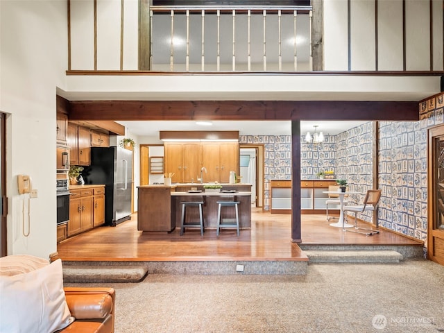 living room with a towering ceiling, light wood-style floors, and a notable chandelier