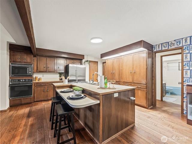 kitchen with black appliances, wood-type flooring, and light countertops