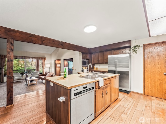 kitchen featuring dishwasher, high quality fridge, open floor plan, light countertops, and a sink