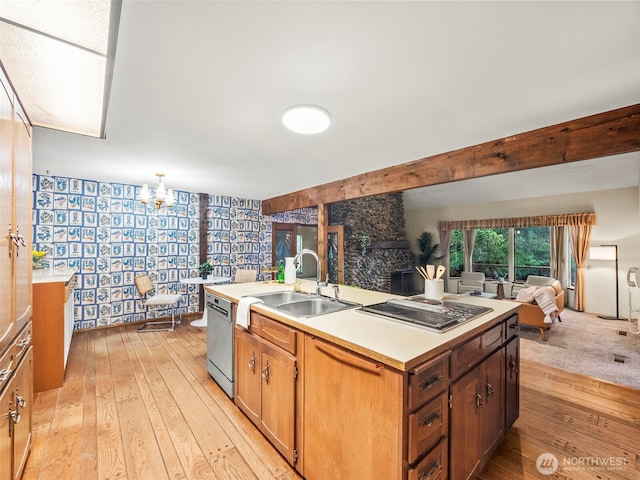 kitchen featuring stainless steel appliances, light countertops, light wood-style floors, open floor plan, and a sink