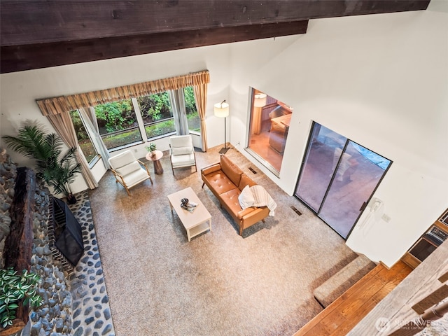 living area featuring lofted ceiling with beams and visible vents