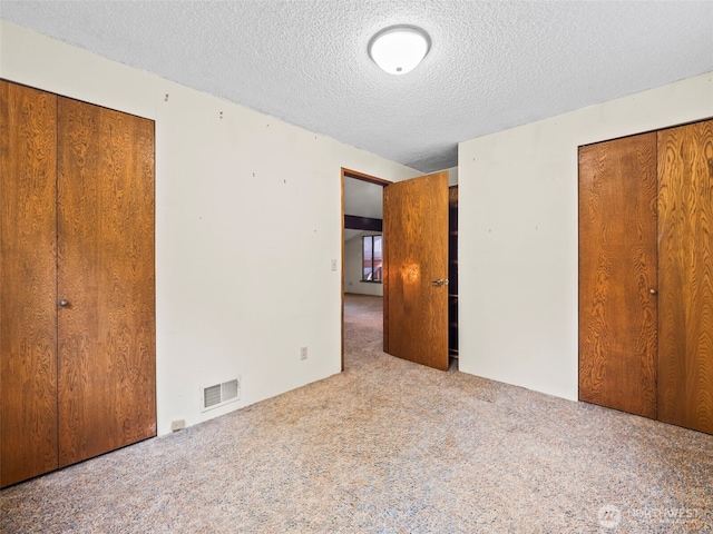 unfurnished bedroom featuring a textured ceiling, carpet flooring, and visible vents