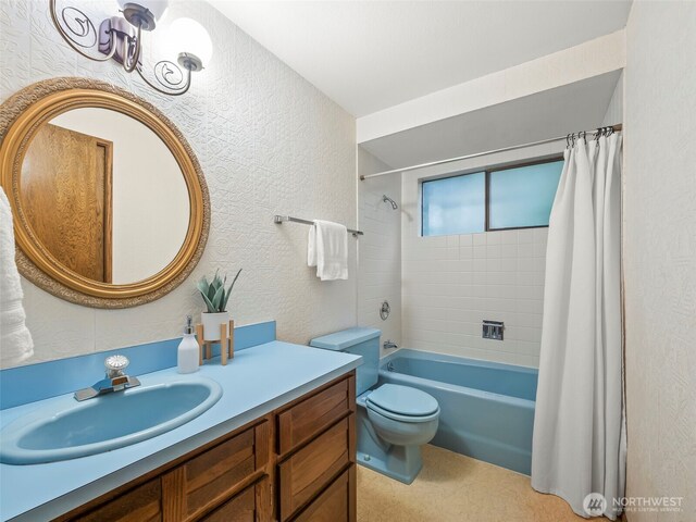 bathroom featuring toilet, vanity, shower / bath combo with shower curtain, and a textured wall