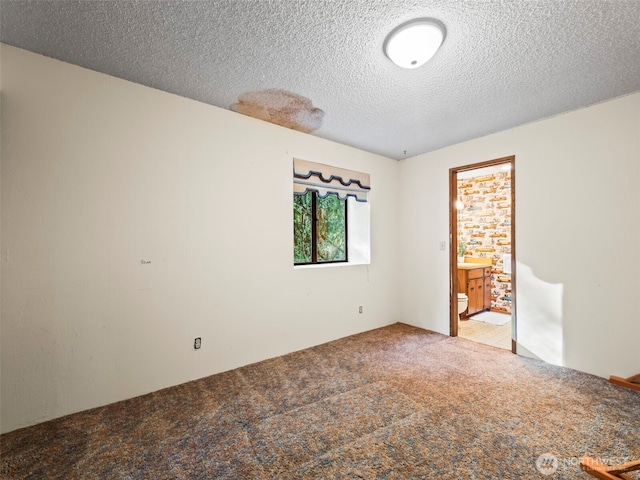 unfurnished bedroom with carpet, a textured ceiling, and ensuite bath