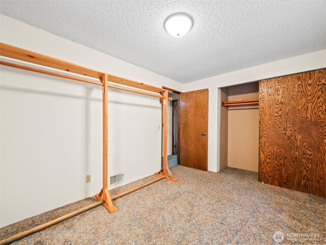 unfurnished bedroom with carpet floors, a closet, visible vents, and a textured ceiling