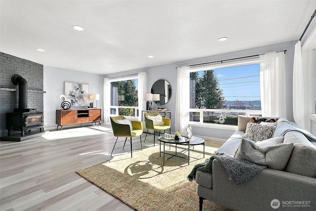 living area featuring a wood stove, baseboards, wood finished floors, and recessed lighting