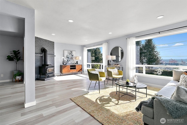 living room featuring recessed lighting, wood finished floors, a wood stove, and baseboards