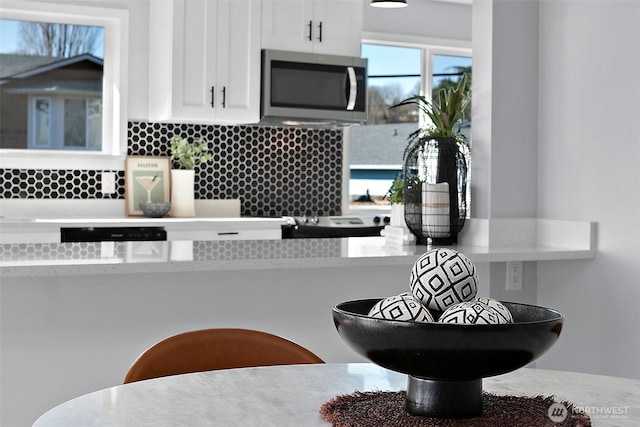 kitchen featuring dishwashing machine, white cabinets, light countertops, decorative backsplash, and stainless steel microwave