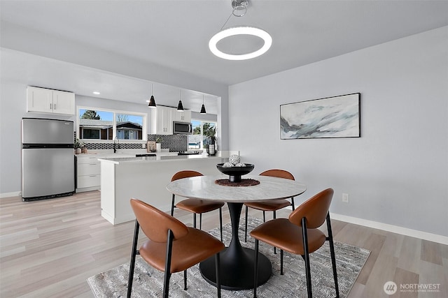 dining space with baseboards and light wood finished floors