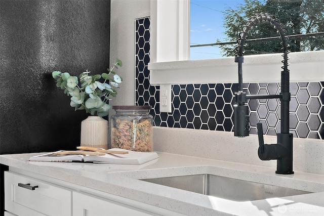 details with white cabinets, a sink, and light stone countertops