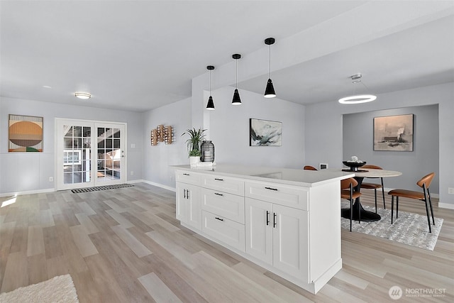 bar featuring hanging light fixtures, light wood-style flooring, and baseboards