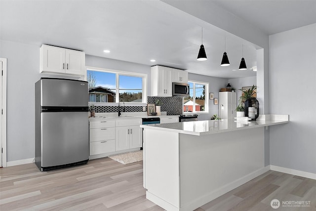 kitchen featuring light wood finished floors, white cabinetry, and appliances with stainless steel finishes