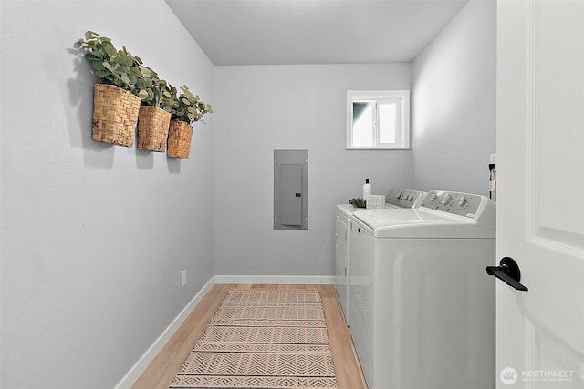 laundry area with light wood finished floors, washer and dryer, laundry area, electric panel, and baseboards