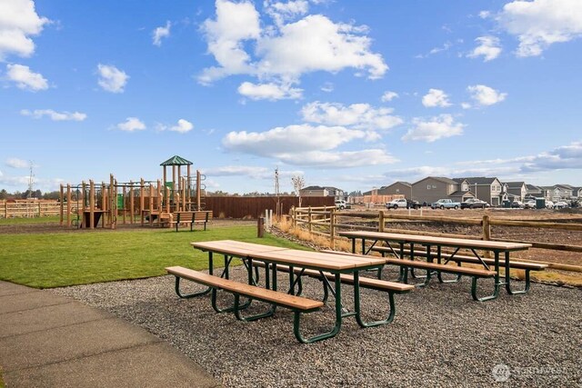 view of property's community with fence, a lawn, and playground community