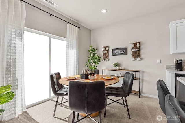 dining room featuring visible vents, light carpet, and baseboards