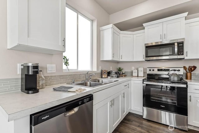 kitchen with stainless steel appliances, light countertops, dark wood-type flooring, white cabinets, and a sink