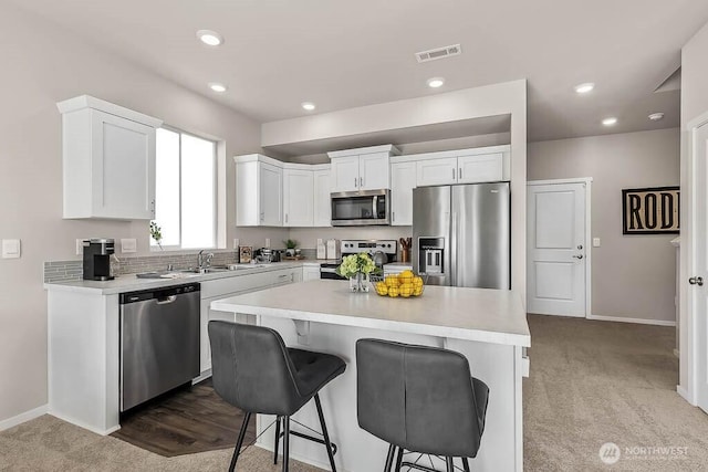 kitchen featuring visible vents, white cabinets, appliances with stainless steel finishes, a kitchen breakfast bar, and light countertops