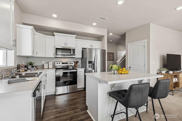 kitchen featuring visible vents, a kitchen breakfast bar, light countertops, stainless steel appliances, and a sink