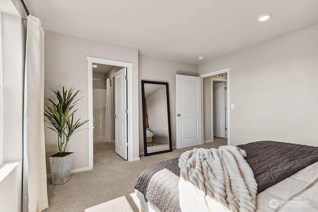 bedroom with light carpet, a spacious closet, and baseboards