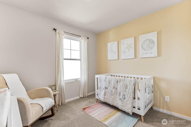 bedroom featuring a crib, carpet flooring, and baseboards