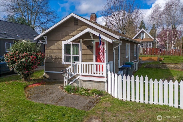 view of front facade featuring a chimney, a front yard, and fence