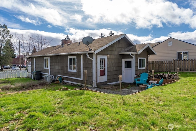 rear view of house featuring a yard and fence