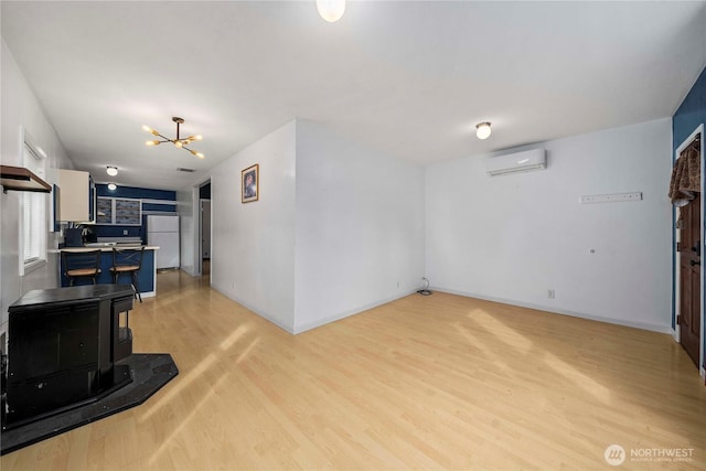 living area featuring a chandelier, light wood-style flooring, baseboards, and a wall mounted AC