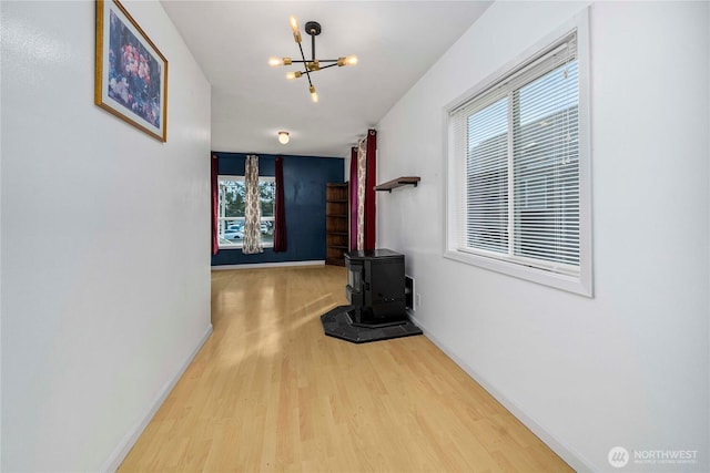 corridor featuring a chandelier, wood finished floors, and baseboards