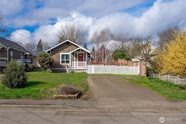 view of front of house with dirt driveway, fence, and a front lawn