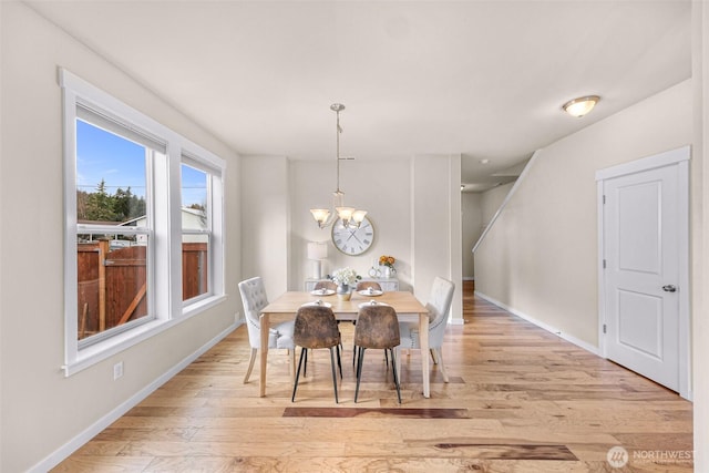 dining space featuring a chandelier, light wood-type flooring, and baseboards