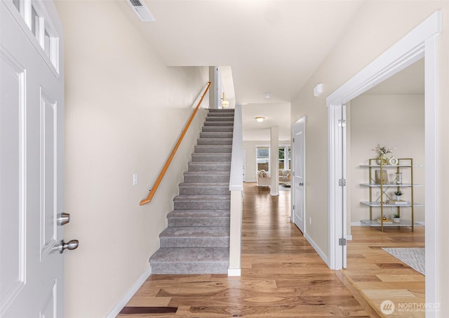 entryway with baseboards, visible vents, light wood finished floors, and stairs