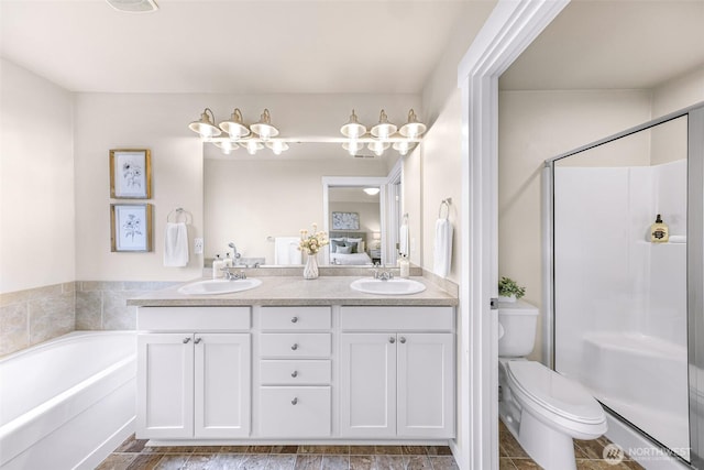 bathroom featuring toilet, a stall shower, a sink, and ensuite bathroom