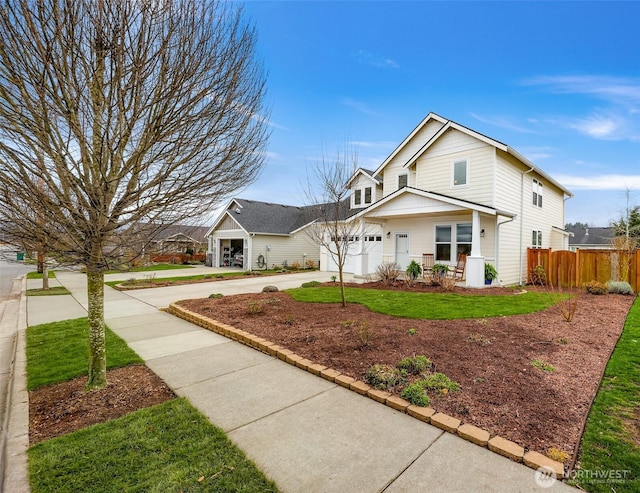 traditional-style house featuring driveway, an attached garage, fence, and a front yard