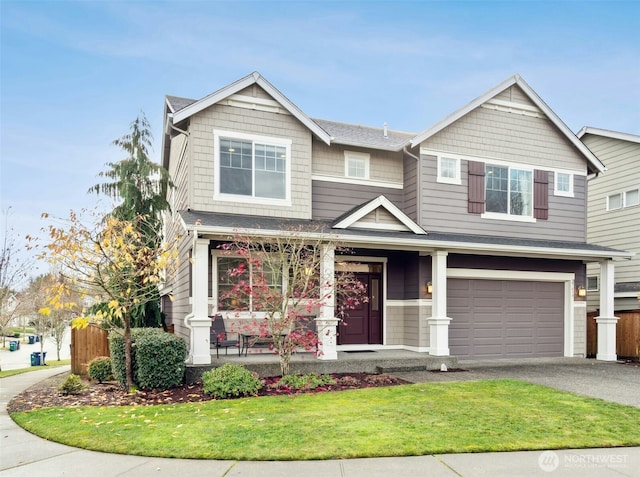 view of front of house with driveway, covered porch, an attached garage, and a front yard