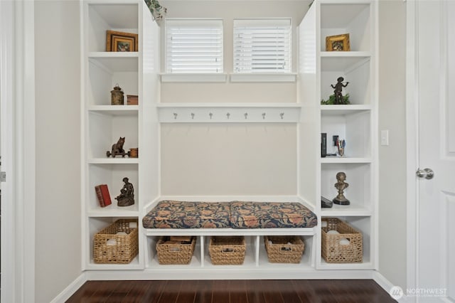 mudroom with built in features, dark wood-style flooring, and baseboards