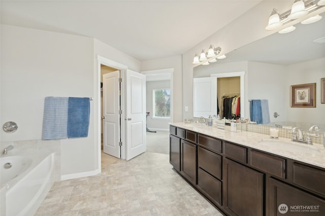 bathroom featuring double vanity, a sink, baseboards, and a bath