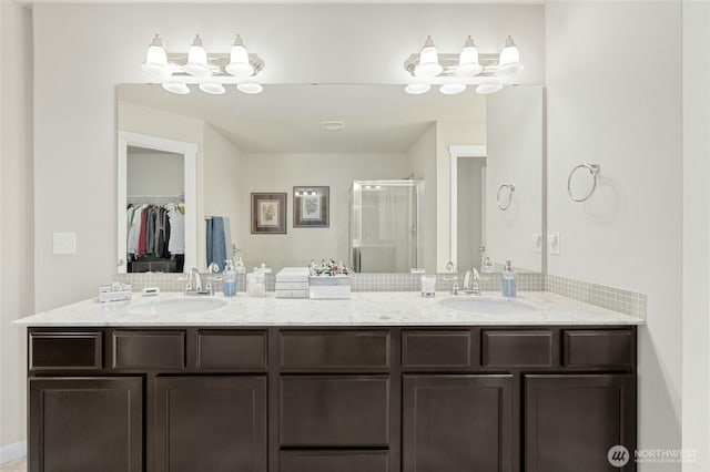 full bathroom with a stall shower, a sink, a spacious closet, and double vanity